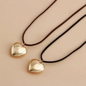 Detalle de grandes colgantes de corazón en oro pulido sobre finos cordones de terciopelo