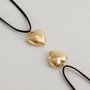 Primer plano de colgantes de corazón dorado en cordones de terciopelo negro y marrón