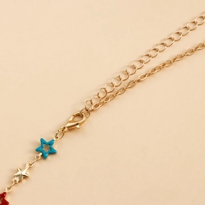 Macro detail of gold-tone body chain with colorful enamel star charms and lobster clasp