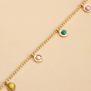 Detailed macro view of a gold beaded body chain featuring colorful enamel round pendants