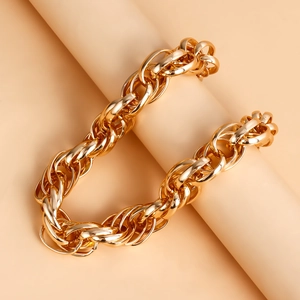 Close-up of a chunky gold-tone chain necklace wrapped on a minimalist prop