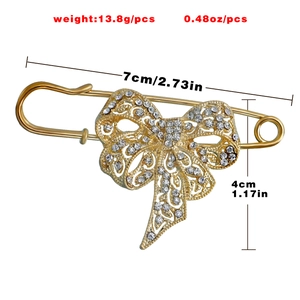 Détail d'une broche nœud dorée vintage ornée de strass brillants et travail de métal