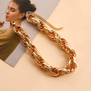Detailed close-up of thick gold-tone aluminum chain necklace with lobster clasp and tail chain