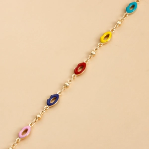 Close-up of colorful enamel lips charms on a gold body chain with fine metal beads