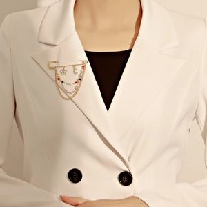 Détail d'une broche épingle dorée avec chaînes et breloques étoile lune sur un blazer
