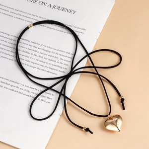 Detalle del colgante de corazón dorado en collar choker de ante negro con cierre metal