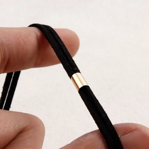 Detalle de cordón de terciopelo negro con deslizador de metal dorado pulido para gargantilla