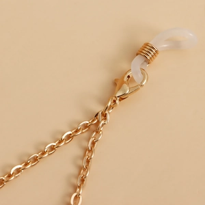 Makrodetail einer goldenen Brillenkette mit Karabinerverschluss und Silikonschlaufe