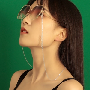 Silver infinity glasses chain with crystal accents worn against a vivid green background