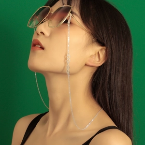 Close-up of silver infinity charm on a delicate eyewear chain worn with sunglasses