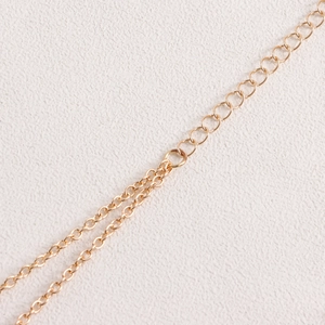 Close-up of golden bikini body chain showing the adjustable extender link and fine clasp detail