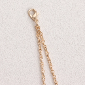 Macro detail of the golden lobster clasp and the double-layer rhinestone chain link