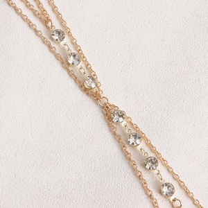 Detail of double-layer gold chain body jewelry with shimmering zircon rhinestones