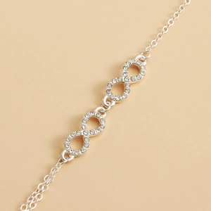 Close-up of infinity symbol chain with white rhinestones in a polished silver finish