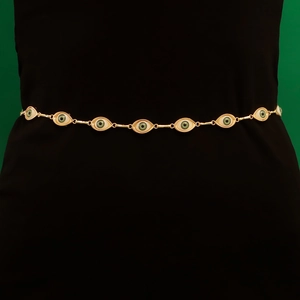 Ethnic style gold body chain featuring green evil eye charms over black attire