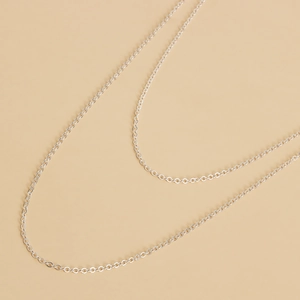 Macro shot of a minimalist silver metal O-link eyewear chain on a beige background