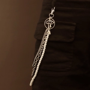 Dettaglio di catena per pantaloni multistrato argento con ciondolo occhio e perle finte
