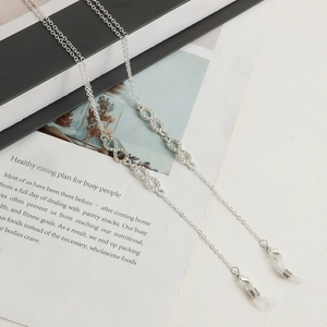 Detail of silver infinity glasses chain with rhinestones on a lifestyle magazine