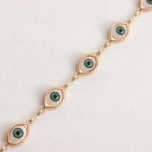 Macro detail of gold evil eye waist chain with green iris pendants and link texture