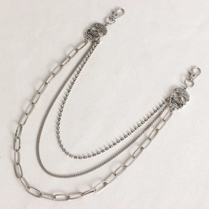 Dettaglio di ciondoli a teschio argento e catene metalliche a tre strati con strass