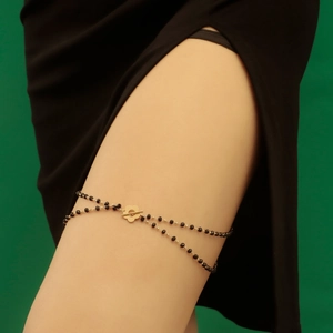 Detail of double-layer black beaded leg chain with a golden flower toggle clasp closure