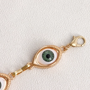 Close-up of golden evil eye waist chain showing fine texture and lobster clasp details
