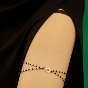 Close-up of double-layer leg chain with black beads and golden flower T-bar closure