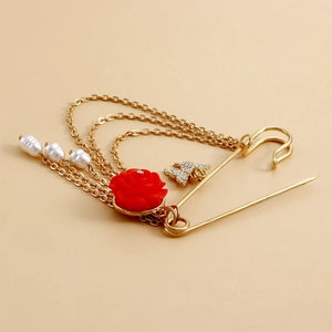 Détail d'une broche vintage avec rose rouge, chaînes, perles et pendentif papillon