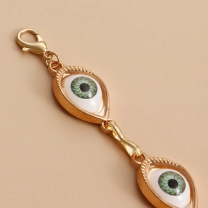 Detail of gold evil eye charms with green iris and lobster clasp for body chain