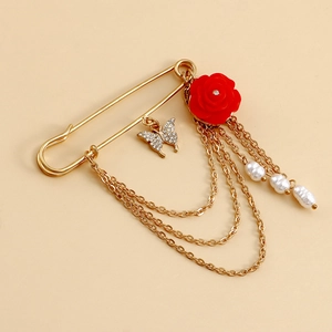 Détail d'une broche épingle vintage avec rose rouge, papillon en diamant et perles