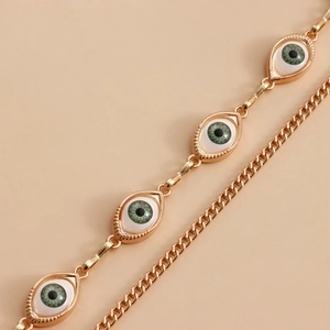 Close-up of golden waist chain featuring green evil eye charms with metallic texture