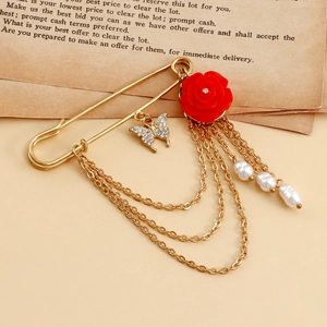 Vue détaillée d'une broche épingle dorée vintage avec rose rouge et glands perlés