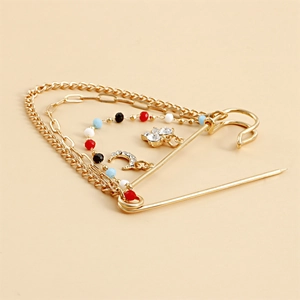 Détail de la broche épingle vintage avec chaînes multicouches, perles et pendentif lune