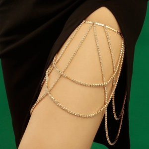 Detail of gold multilayer leg chain with rhinestones and fringes on a model wearing black