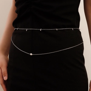 Detail of double-layer silver waist chain with small beads and white pearl on black dress