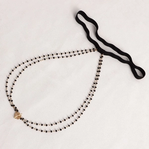 Detailed macro view of black beaded leg chain with golden OT buckle and elastic band