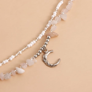 Detail of bohemian waist chain with white beads, pink stones, and crescent moon pendant