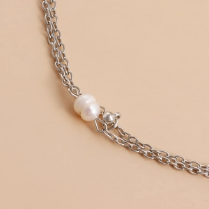 Detailed macro view of silver layered chain with white freshwater pearl and polished bead