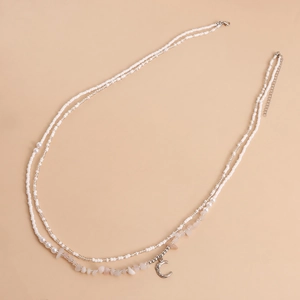 Detail of bohemian white seed bead waist chain with crescent moon and pink gravel stone
