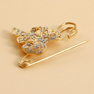 Vue macro d'une broche ange dorée avec strass scintillants sur fond beige clair