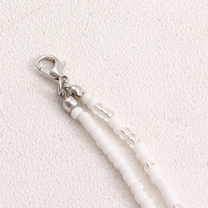 Detailed macro view of silver lobster clasp and white beads on Bohemian waist chain
