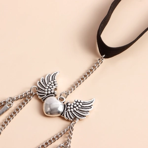 Detail of a black elastic leg chain with a silver winged heart pendant and metal chains
