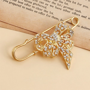 Gros plan sur une broche nœud dorée sertie de strass sur un fond de papier vintage