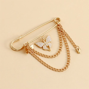 Détail d'une broche papillon dorée avec perles d'imitation et chaînes multicouches