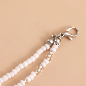 Detailed close-up of double-layered white seed beads and silver lobster clasp connector