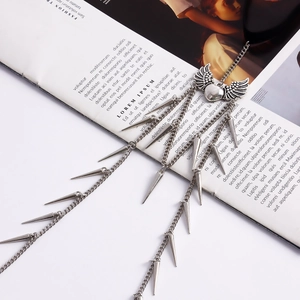 Detailed close-up of heart wing pendant and metallic spikes on multi-layered leg chain