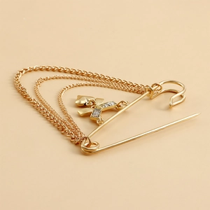 Détail de broche épingle dorée avec trois chaînes et pendentif arc en zircon