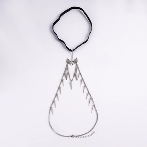 Detail of gothic leg chain with black elastic band, silver heart wing, and metal spikes