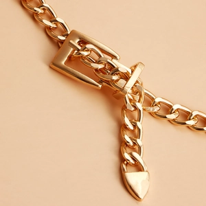 Close-up of golden chunky cuban chain belt featuring a minimalist heart-shaped pendant