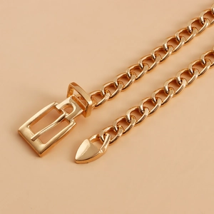 Close-up of golden metal thick chain belt with polished buckle and triangle pendant